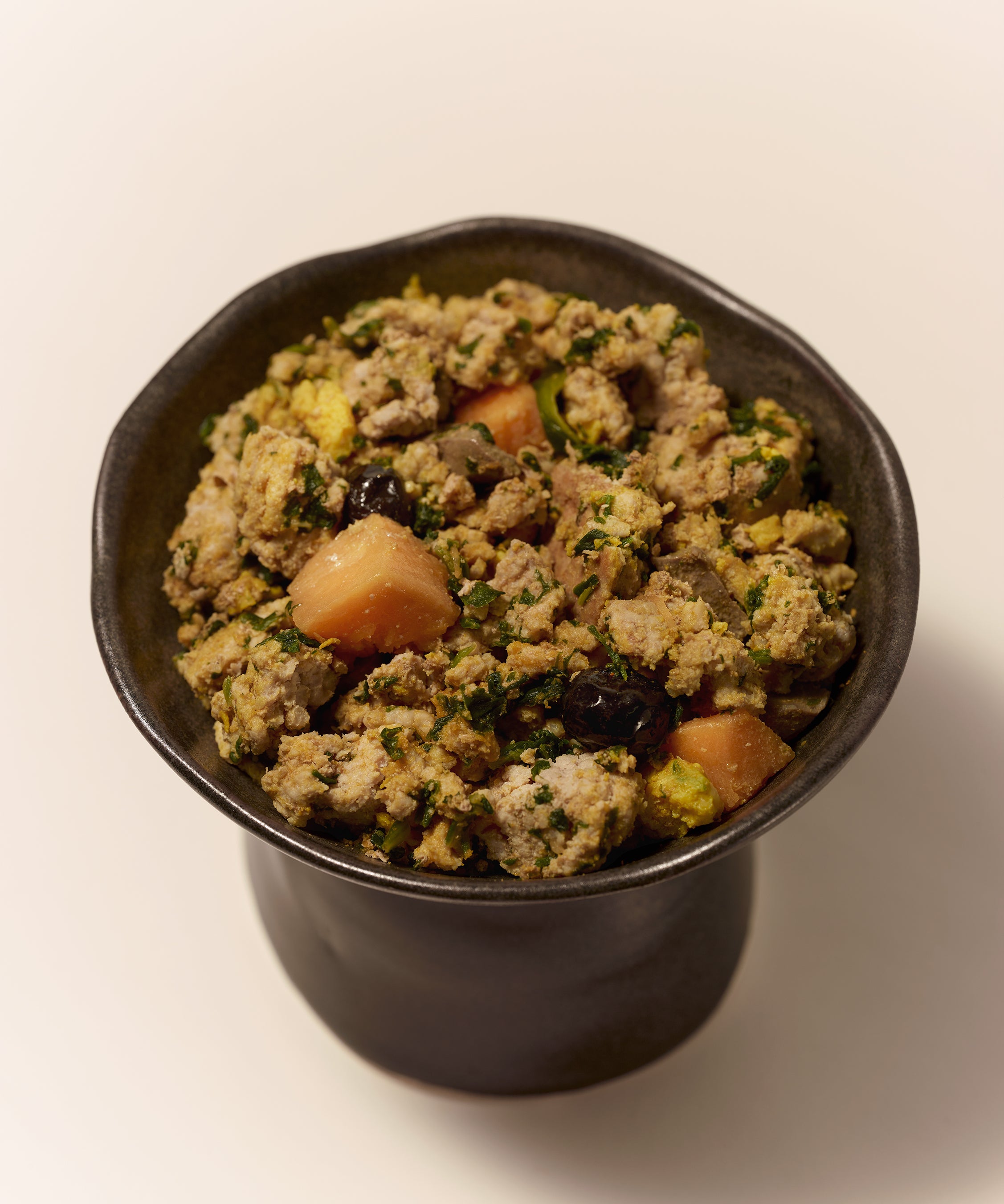 Purely Golden Foods turkey dog food served in a dark ceramic bowl, showing visible whole food ingredients including pumpkin, spinach, egg, and blueberries