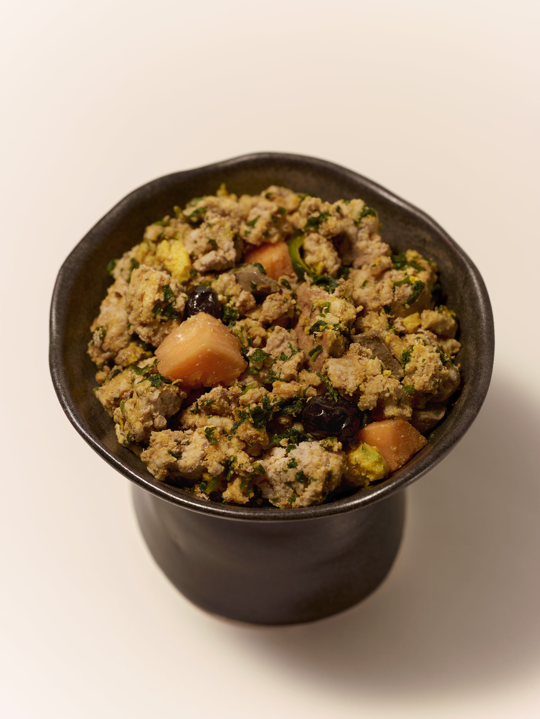 Purely Golden Foods turkey dog food served in a dark ceramic bowl, showing visible whole food ingredients including pumpkin, spinach, egg, and blueberries