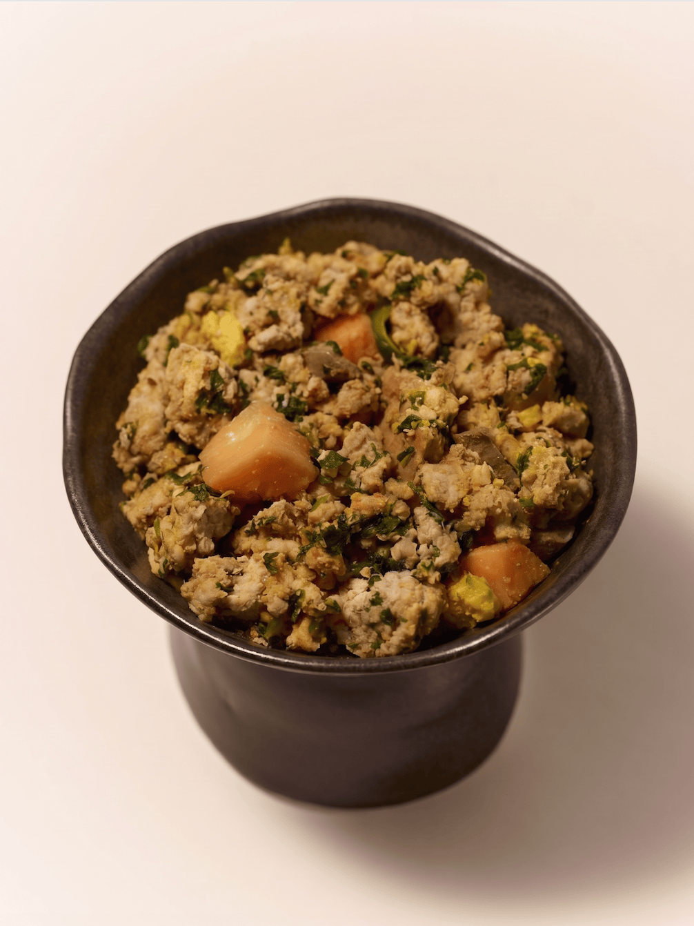 Purely Golden Foods turkey dog food served in a dark ceramic bowl, showing visible whole food ingredients including pumpkin, spinach and egg.