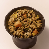 Purely Golden Foods turkey dog food served in a dark ceramic bowl, showing visible whole food ingredients including pumpkin, spinach and egg.
