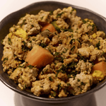 Close-up of Purely Golden Foods turkey dog food in a dark ceramic bowl, with visible chunks of pumpkin, spinach and egg
